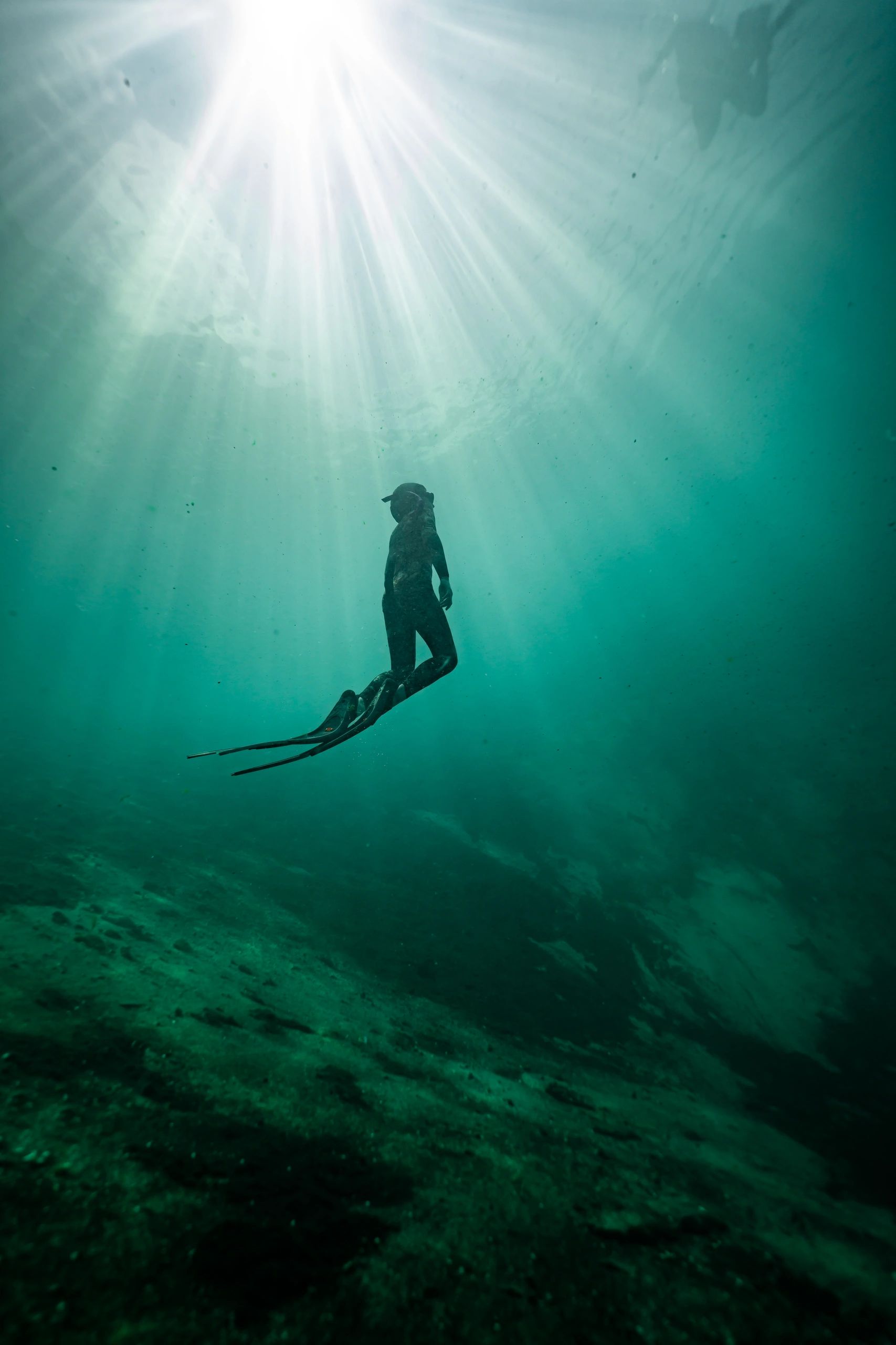Freediver ascending toward the surface with sunlight rays