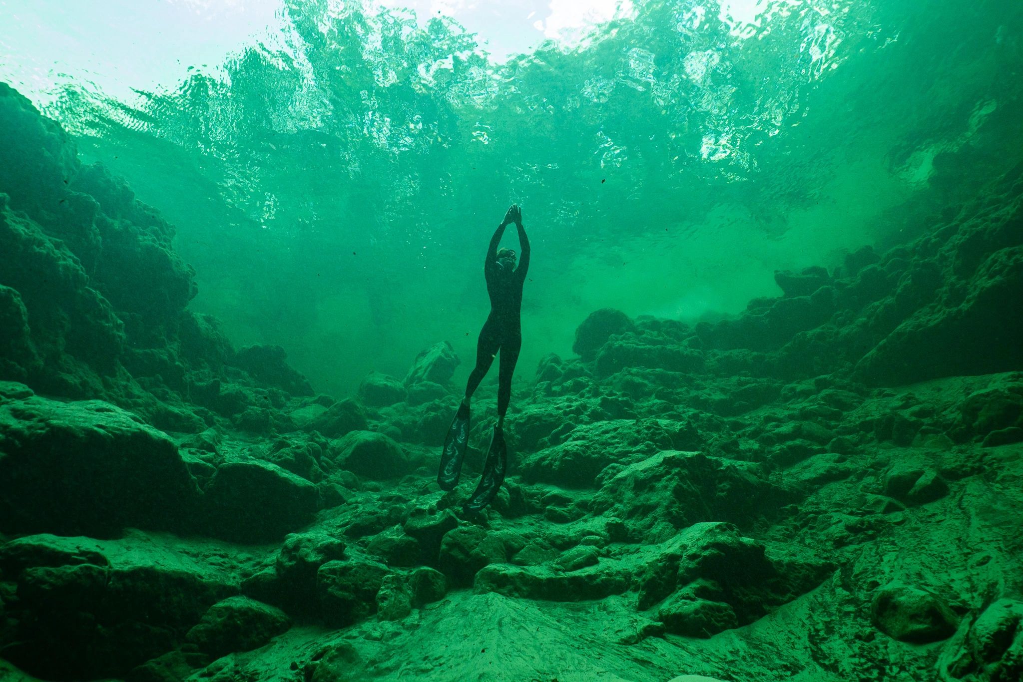Freediver exploring an underwater rocky canyon